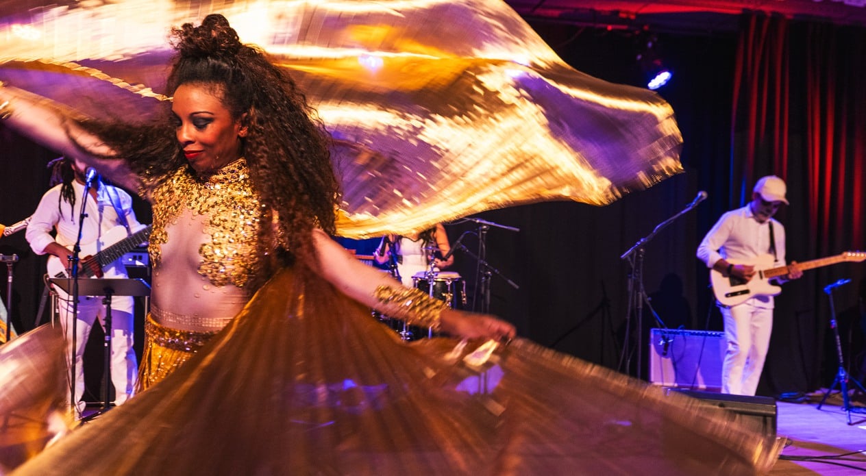 Woman in golden dress dancing at a noche de muertos party